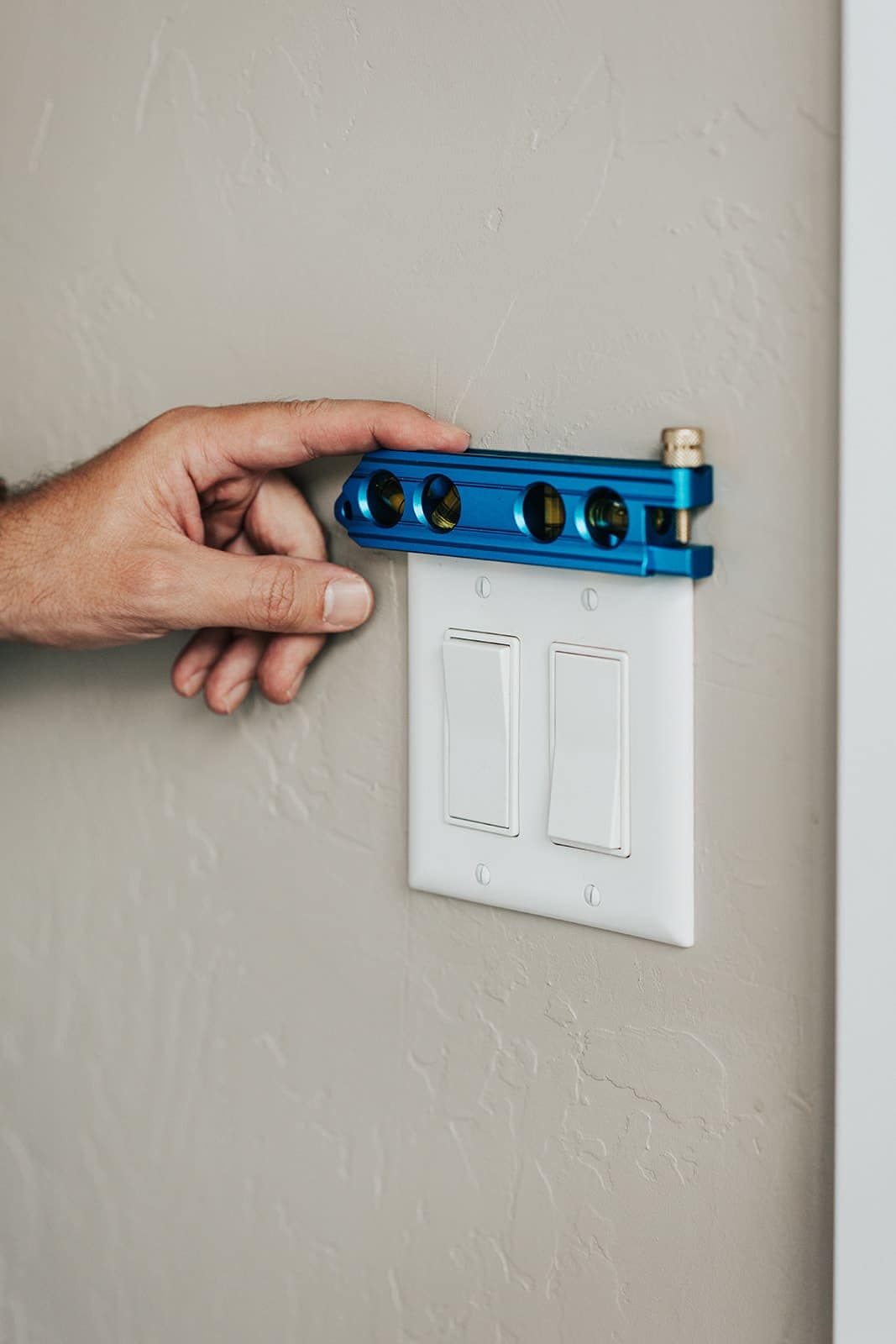 Levelling a two-gang switch plate against a hallway wall