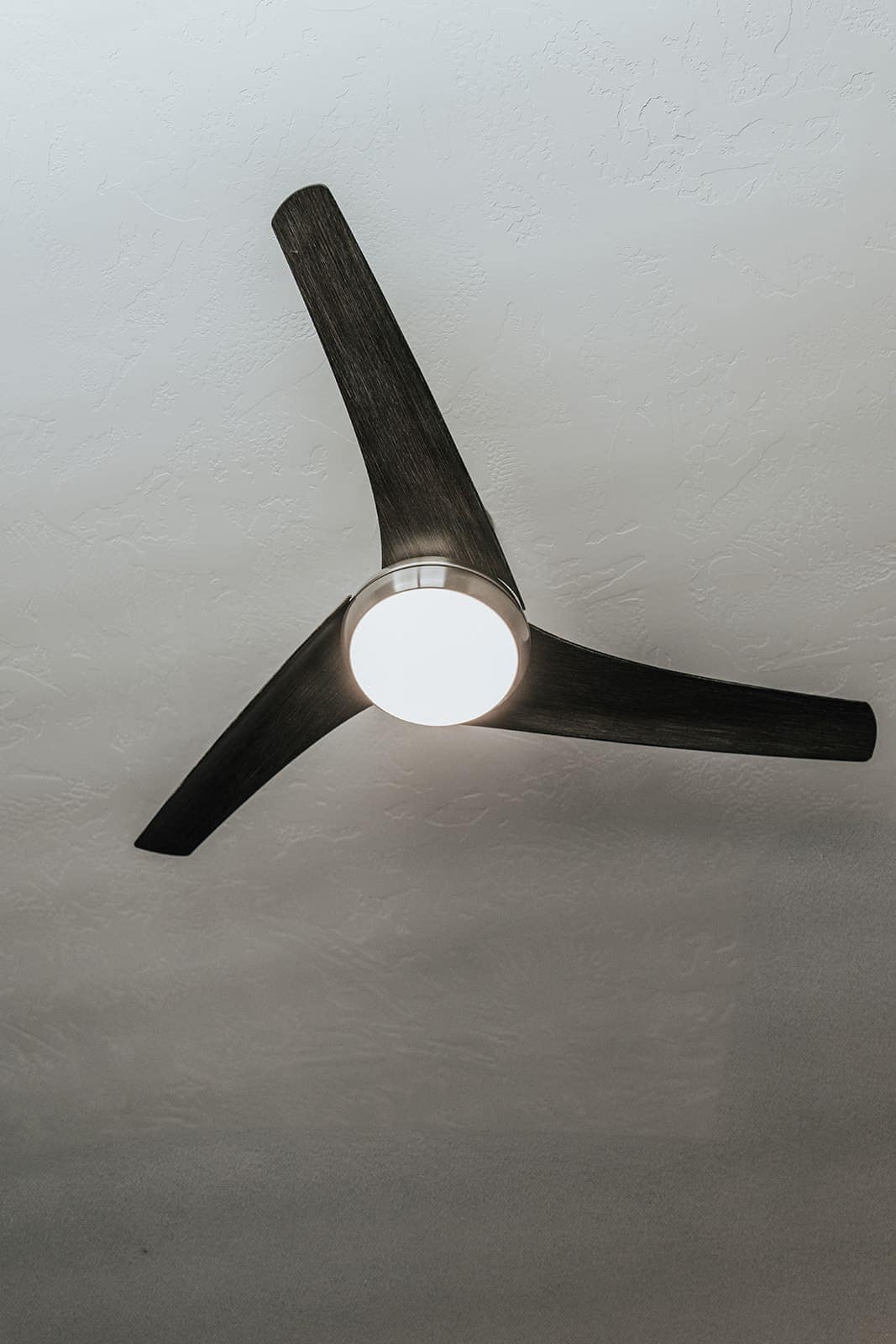 A modern three blade ceiling fan with light kit, installed and balanced